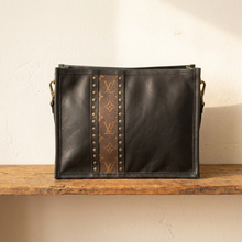 Load image into Gallery viewer, A black leather crossbosy bag with a central brown LV monogram stripe and brass-tone studs.