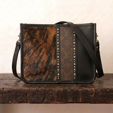 Load image into Gallery viewer, Crossbody bag featuring a dark Brindle cowhide panel, a brown monogram canvas panel, and black leather side panel and trim. Embellished with bras studs and clear crystals.